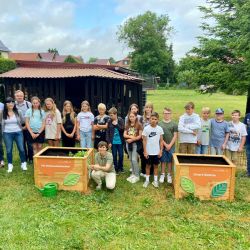 Die Umweltschüler*innen und Gäste an den zwei neuen Hochbeeten - farbenfroh laden sie nun zum Gärtnern ein.